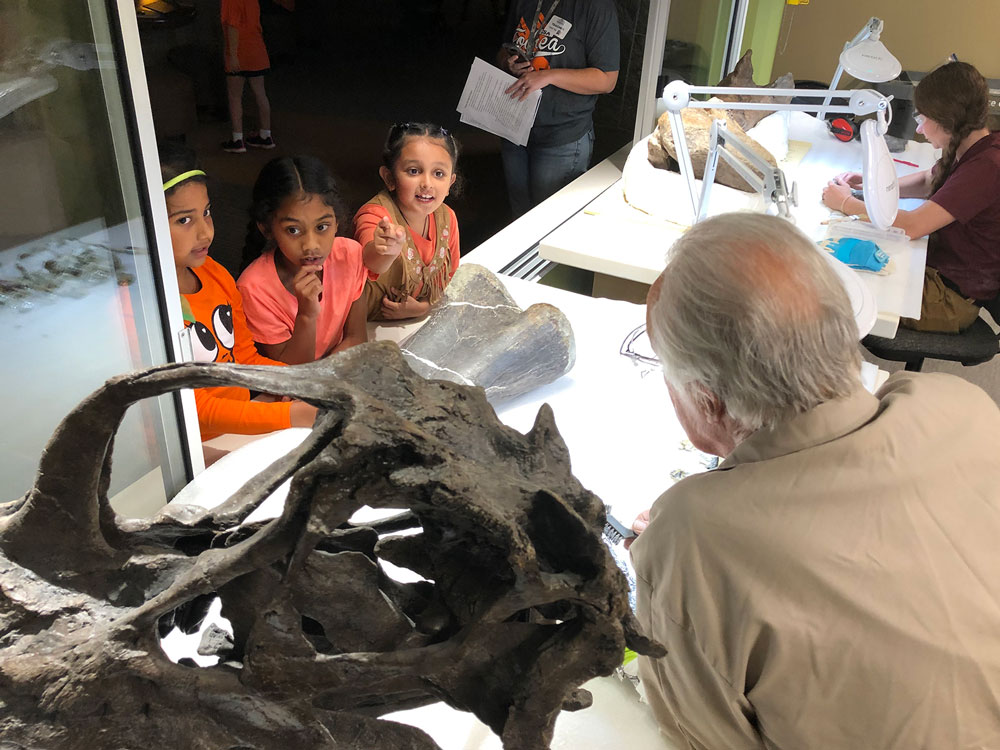 Children talking to a paleontologist in the Dinosphere Paleo Lab.
